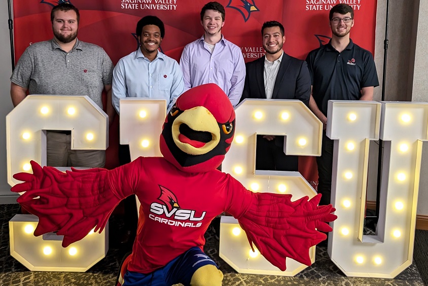 graduates posing with Coop behind the SVSU sign at Senior Toast