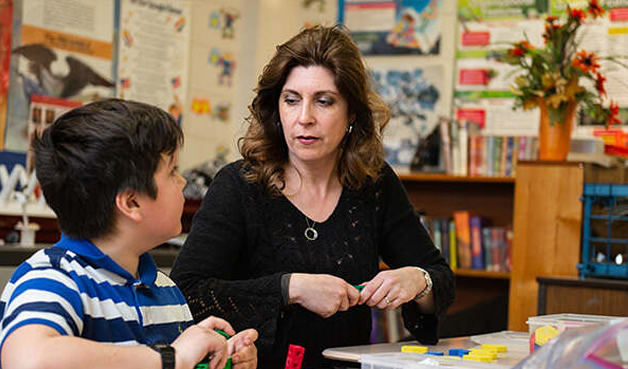 Teacher with student at table with instructional blocks