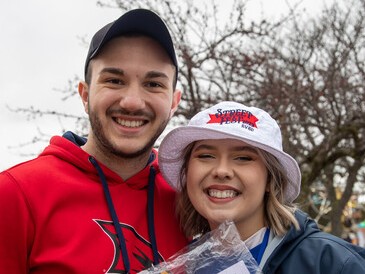 Young man in baseball cap standing next to young woman in bucket hat