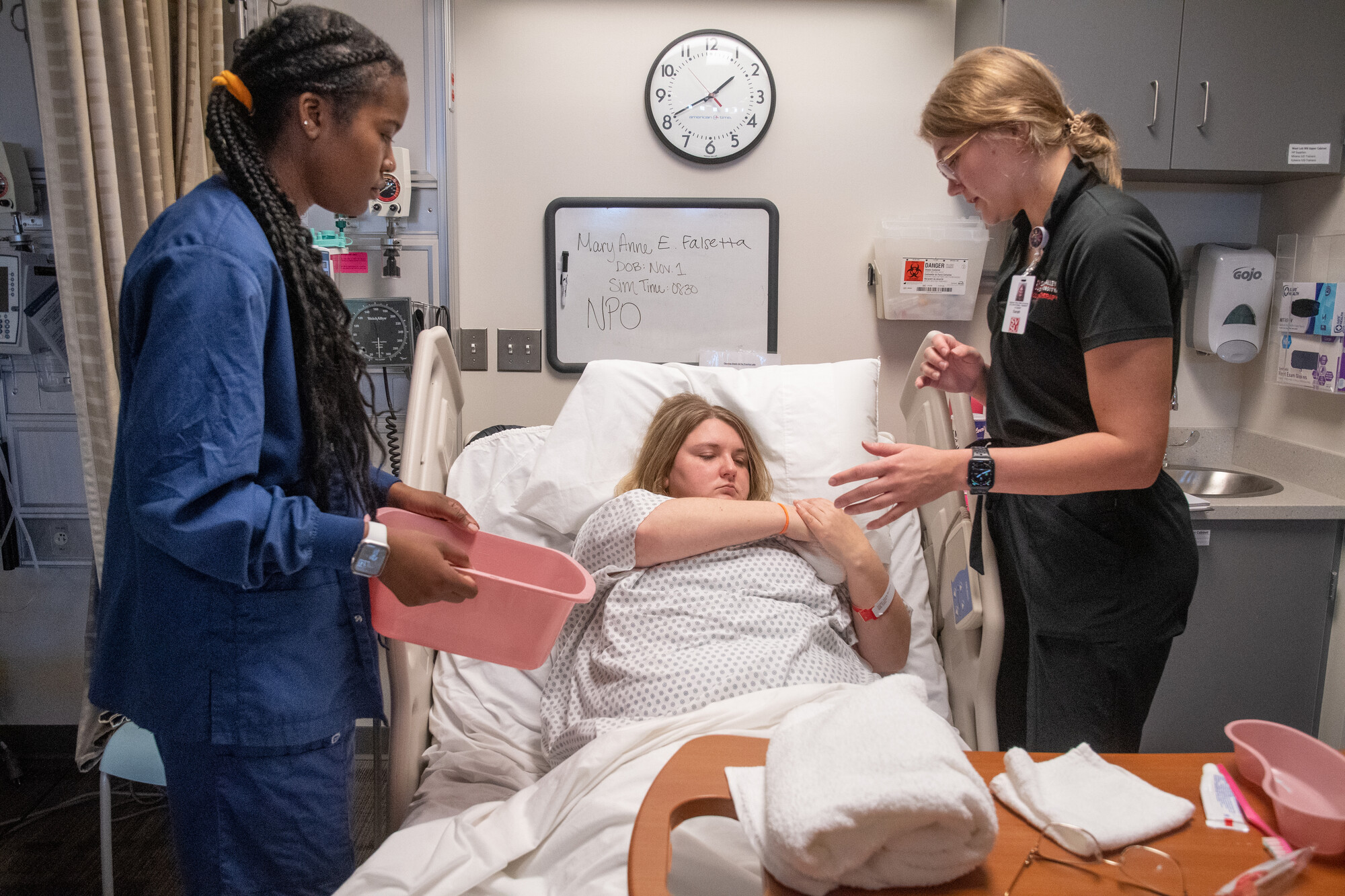 Two nursing students stand at beside of female patient
