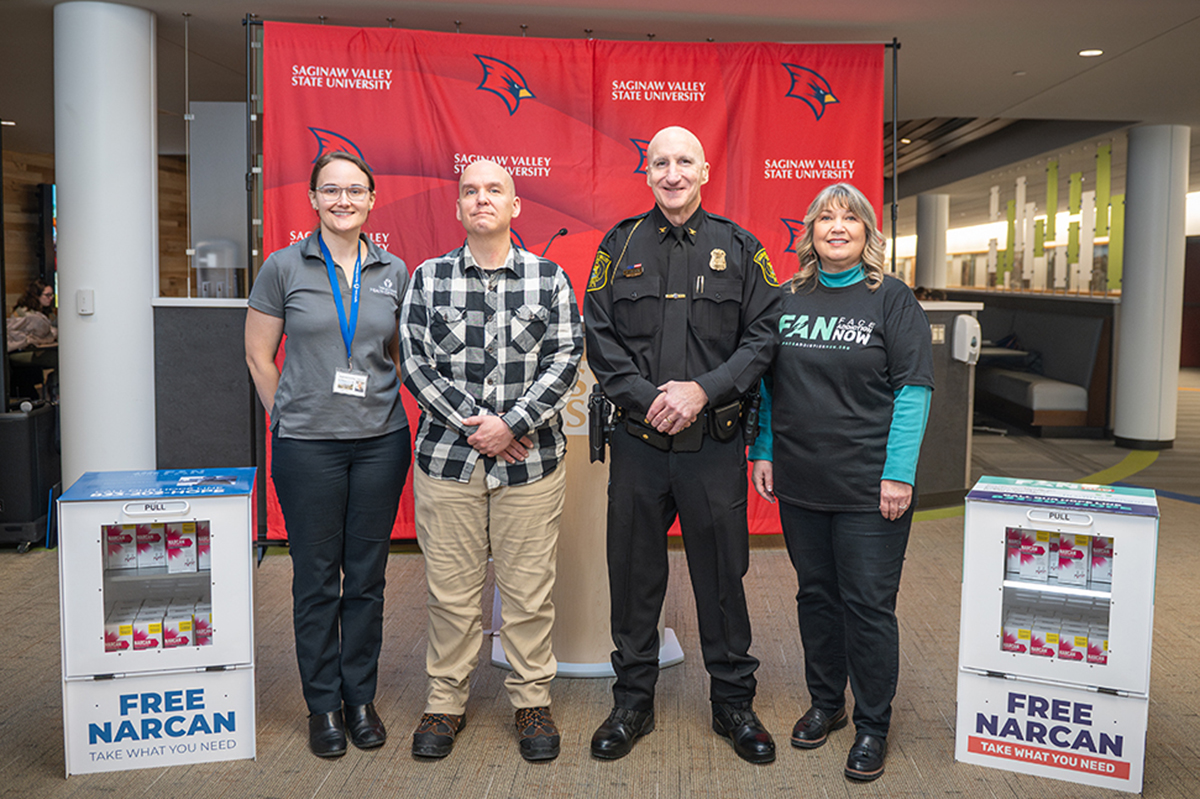 People standing between NARCAN distribution boxes