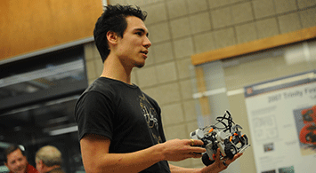 High school student holding a LEGO robot.